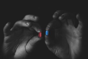 Two hands each holding a red and blue pill representing making a choice between what is real and what is fiction.